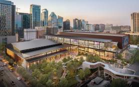 Rendering of the new Austin Convention Center building at sunset with the city skyline in the background. The image shows Waterloo Greenway creek and greenspace in the foreground