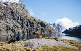 People having a picnic next to a high alpine lake with a helicopter next to them