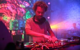 DJ Lefty turns knobs on a deck in a darkened club.