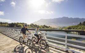 A couple biking the Queenstown Trail with the Remarkables Mountains in the background
