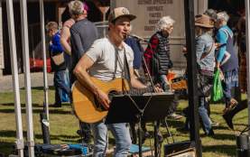 A man playing a guitar under a tent at a market.