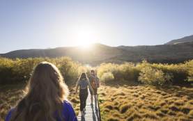 Photo from the point of view walking along the Glenorchy walkway with mountains and the rising sun ahead