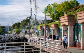 People walking along the harbourfront past shops.