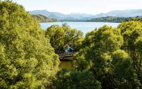 People walking the Lake Hayes loop track surorunded by trees with a view of lake and mountains in the background