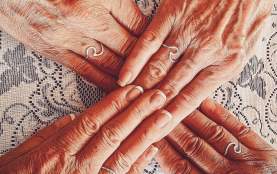 Four people putting their hands together, creating an X shape.