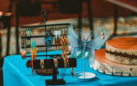 Indigenous jewelry on jewelry stands, one is shaped like a butterfly for earrings and the others are cylindric in shape for rings.