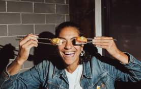 A person using chopsticks to hold sushi up to their eyes.