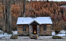 Person sits outside histroric Police Hut Arrowtown