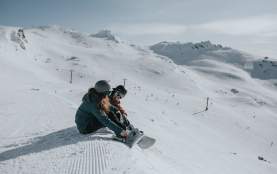 Couple strapping on snowboards at Cardrona Alpine Resort