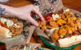 a person reaches for a fried shrimp po-boy and and french fries at Mahony's in New Orleans