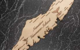 A wooden magnet of Vancouver Island with names of cities and towns on the island.