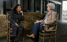 Two women in a barn in rocking chairs having a conversation