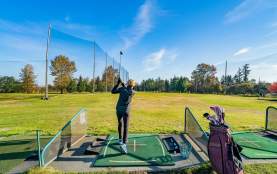A person hitting a golf ball from a driving range.