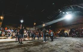 Group of people getting ready to perform a drum in front of a large audience.