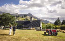 Two people walking along a lawn towards a restaurant with views of mountains in the background
