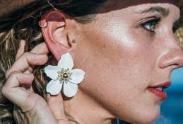 Close up shot of a woman wearing large white floral earrings