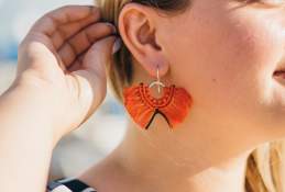 Close up shot of a pair of red fluffy earrings being word by a woman looking away from camera