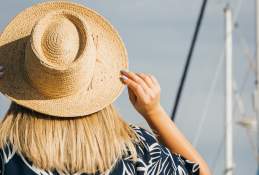 A shot from behind a girl wearing a hat. The background is a marina of boats.