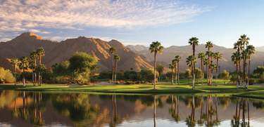 Beautiful lake at Indian Wells Golf Resort with the mountains, palm trees and green grass.