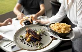 A waitress serves two plates of food to a table.