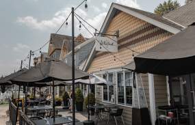 The outside of The Whitlock restaurant with tables and umbrellas.