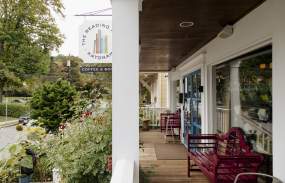 The porch of the Katonah reading room surrounded by rose bushes and with red bench seating.