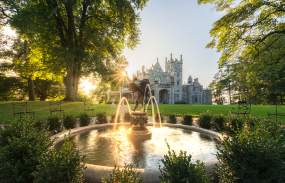 The sun sets over the Hudson River behind Lyndhurst Mansion.