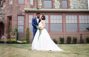 A bride and groom pose on the lawn outside The Abbey Inn.