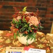 Orange and yellow flowers on a table with a program for the 99th annual celebration of business and community for the Devils Lake, ND Chamber.