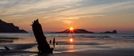 view of the helvetia shipwreck in rhossili against the sunset