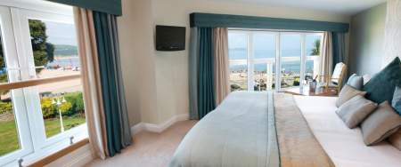 hotel bedroom with double bed and windows looking out over oxwich bay