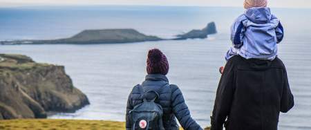 A man and a woman looking out at Worm's head. The man has a child on his shoulder.