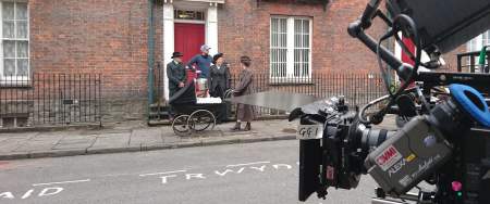 Film set on a street in swansea with cameras and actors standing in a doorway