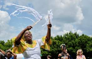 African American woman in traditional dress waving ribbons in the sky