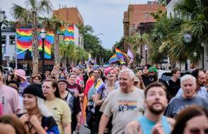 Group of people celebrating Pride in the street with rainbow flags in background