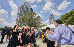 Young ladies in matching blue dresses welcome Amtrak train passengers with skyscrapers in the background
