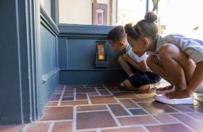 Two children kneeling down to look in a fairy door