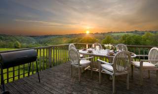 Landscape shot of sunset from the deck of a glamping tent with a set table and chairs in the foreground