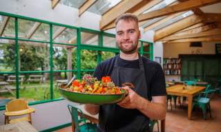 A chef holds a large dish of food in the cafe at The Organic Farm Shop & Cafe, Abbey Home Farm