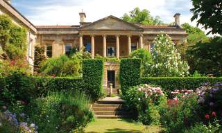 The impressive house at Kiftsgate Court Gardens surrounded by topiary trees and flowering shrubs and