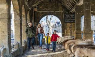 Family with Mother, Father and children walking though Woolmarket House in Chipping Campden. Furs for sale in foreground
