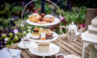 Three tiered afternoon tea selection of cakes, sandwiches and a tea pot at Amberley Castle