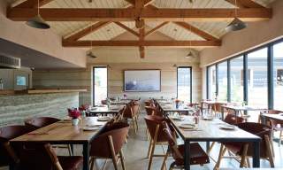Interior view of wooden tables, chairs and beams in Knepp Wilding kitchen restaurant
