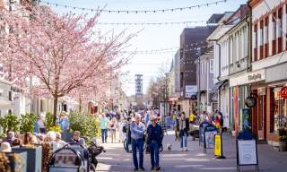 Mennesker som går i gågata og sitter på uteserveringen i Sarpsborg sentrum. Foto.