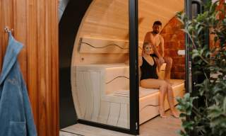 Couple sit in a sauna pod as part of a spa day experience