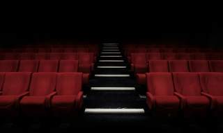 Photograph showing red cinema chairs in a row with an aisle down the middle