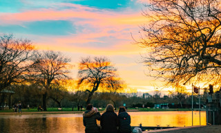 The sun sets over the River Avon as three tourist sit and watch
