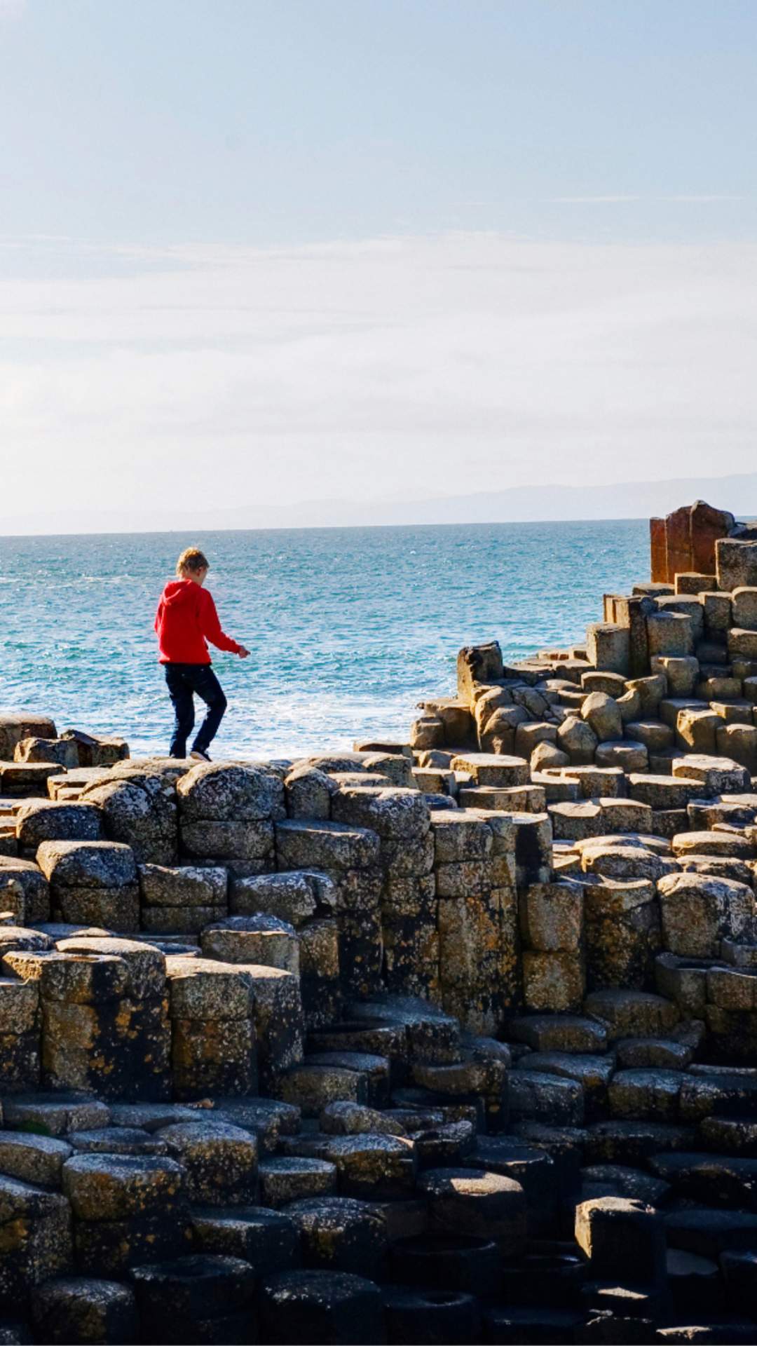 Visitors exploring the basalt columns of the Giant's Causeway on Northern Ireland's north coast, with dramatic coastal scenery and the Atlantic Ocean beyond.