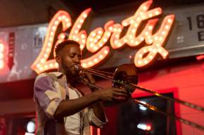 Austin musician Daniel Fears plays the trombone in front of The Liberty bar's lighted sign
