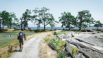 A person hiking on a gravel path by the ocean.